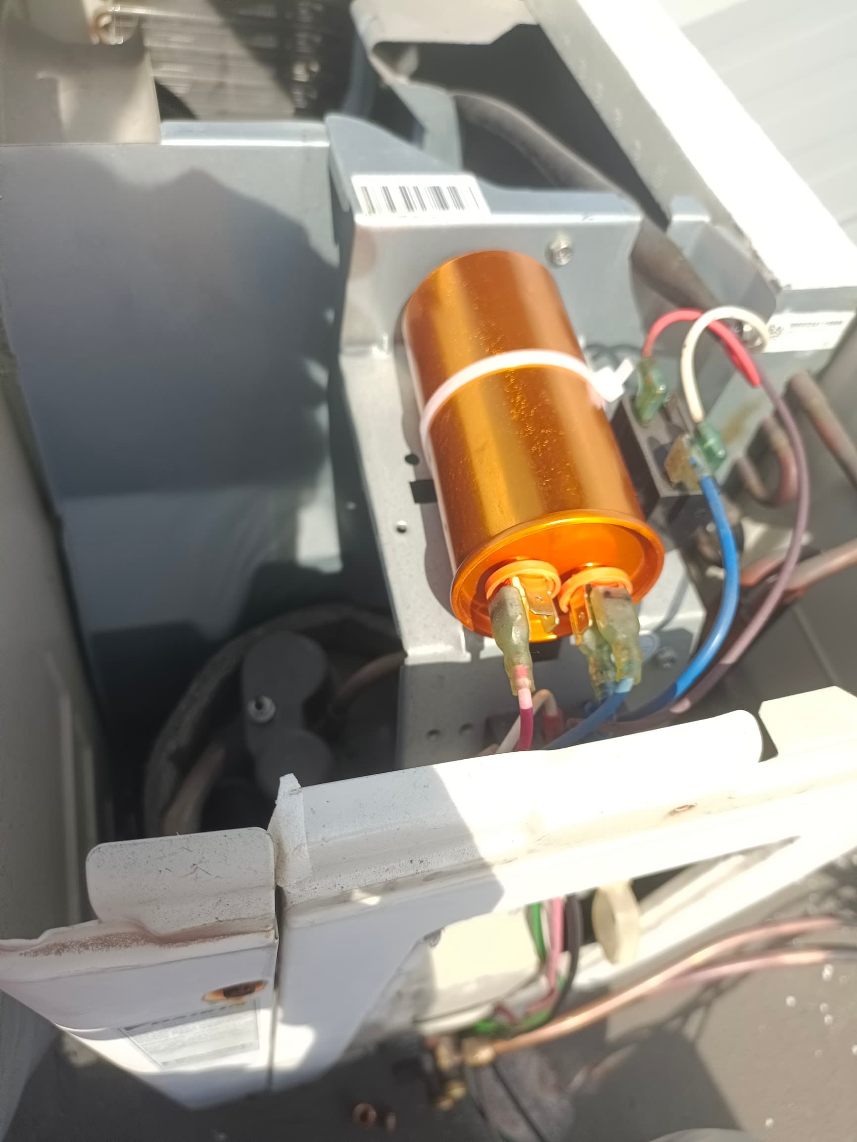 Run capacitor mounted inside an aircon outdoor unit with the cover panel removed